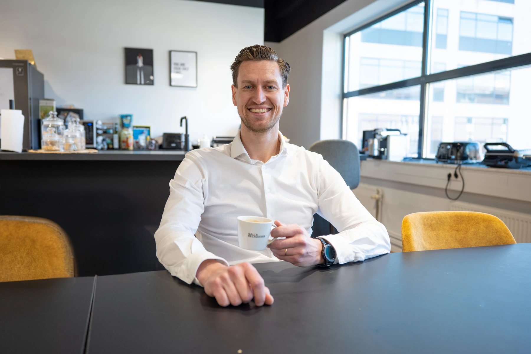 Medewerker aan een tafel met een kop koffie